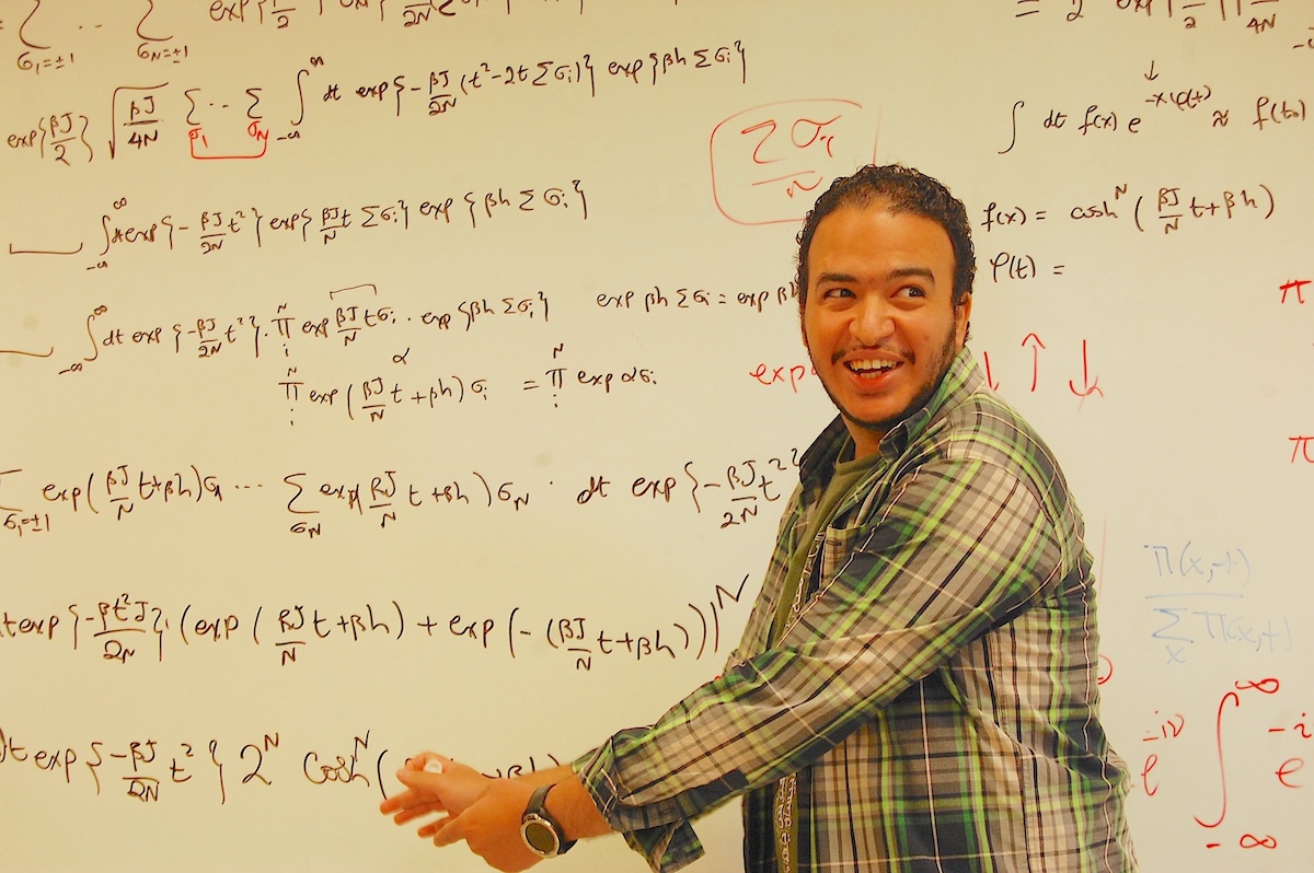 Eslam Abdelaleem, an Emory graduate student, gestures toward equations on a whiteboard while presenting research on artificial intelligence.